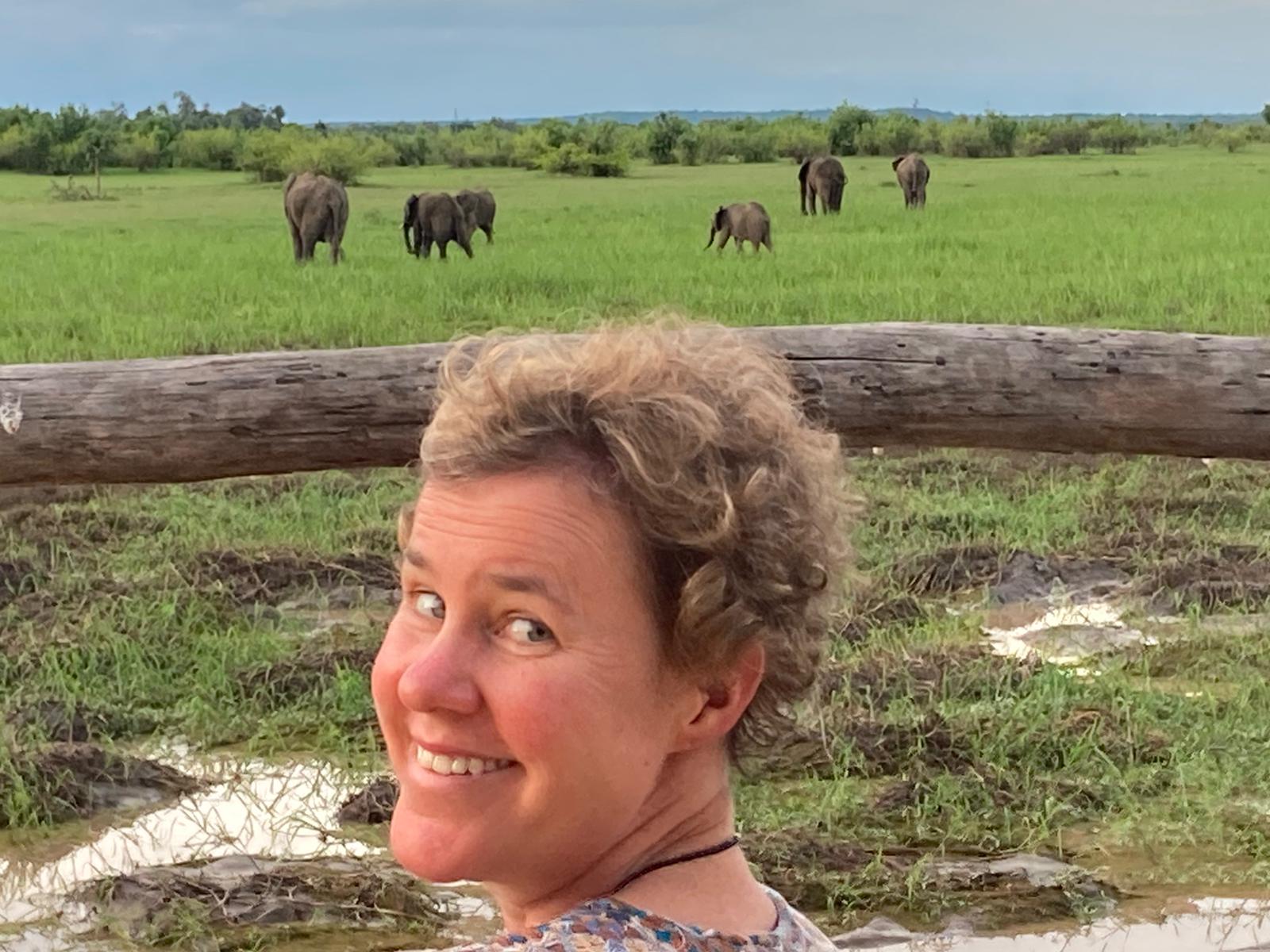 Woman looking over her shoulder smiling with elephants in the background