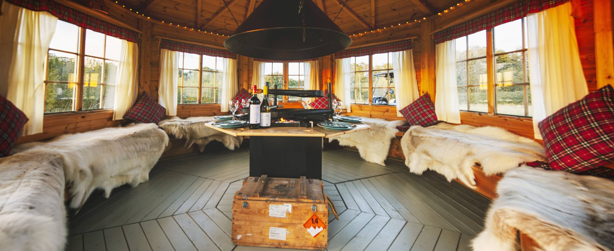 Inside of an octagonal BBQ hut with cosy decor and hides