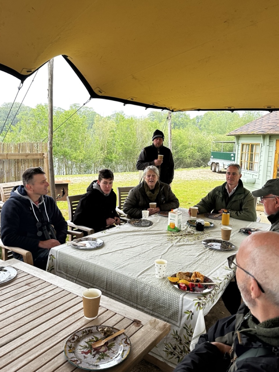 People outside in a stretch tent eating breakfast