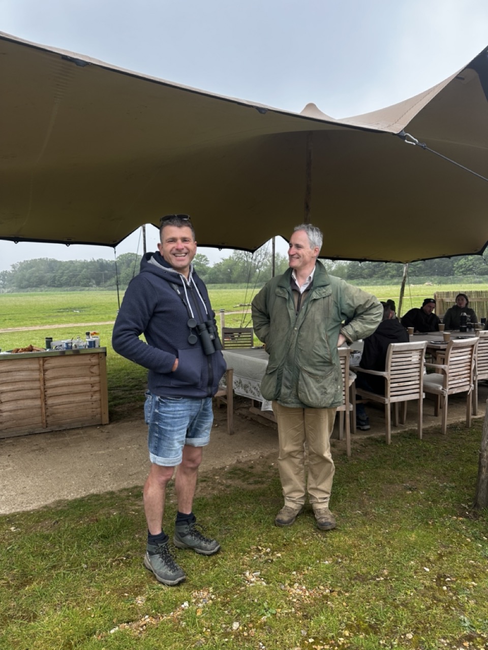 Two men standing outside a stretch tent in a wildlife reserve