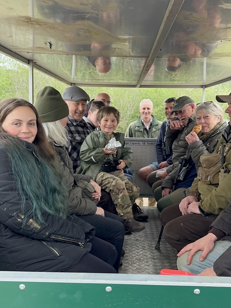 An open-sided trailer with smiling people inside