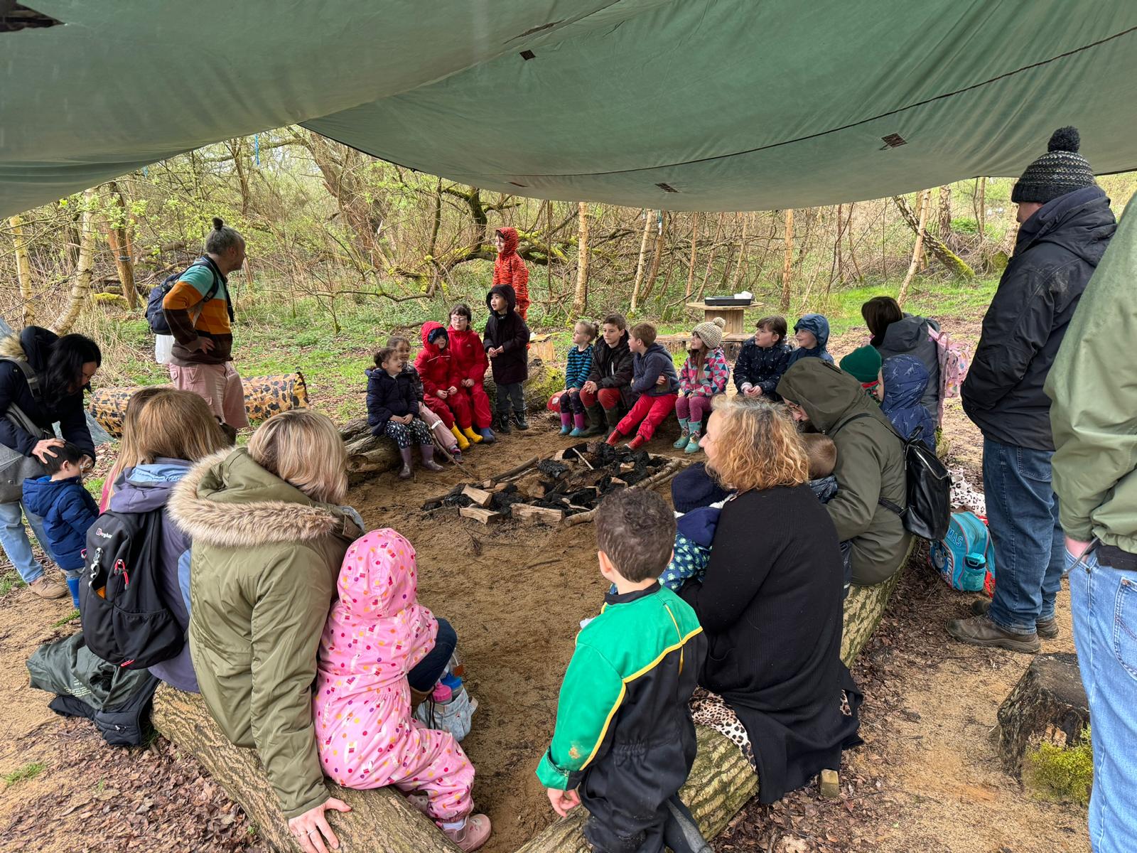 children and families under a canopy around a fire